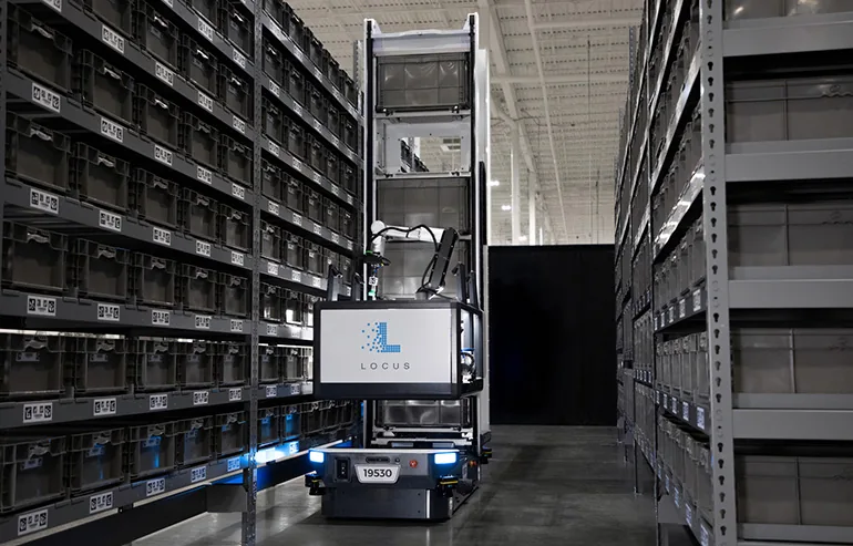 Locus Array puede maniobrar a centímetros de estanterías de doble profundidad y realizar picking hacia contenedores con su sistema de pinzas. Fuente: Locus Robotics