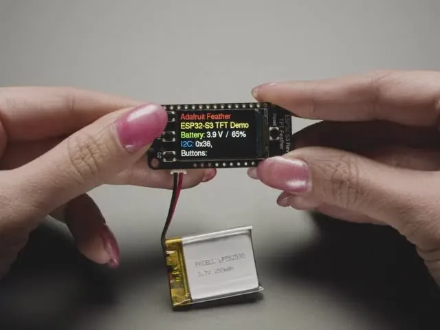 ESP32-S3 Reverse TFT Feather con su pantalla a bordo y una batería LiPo conectada