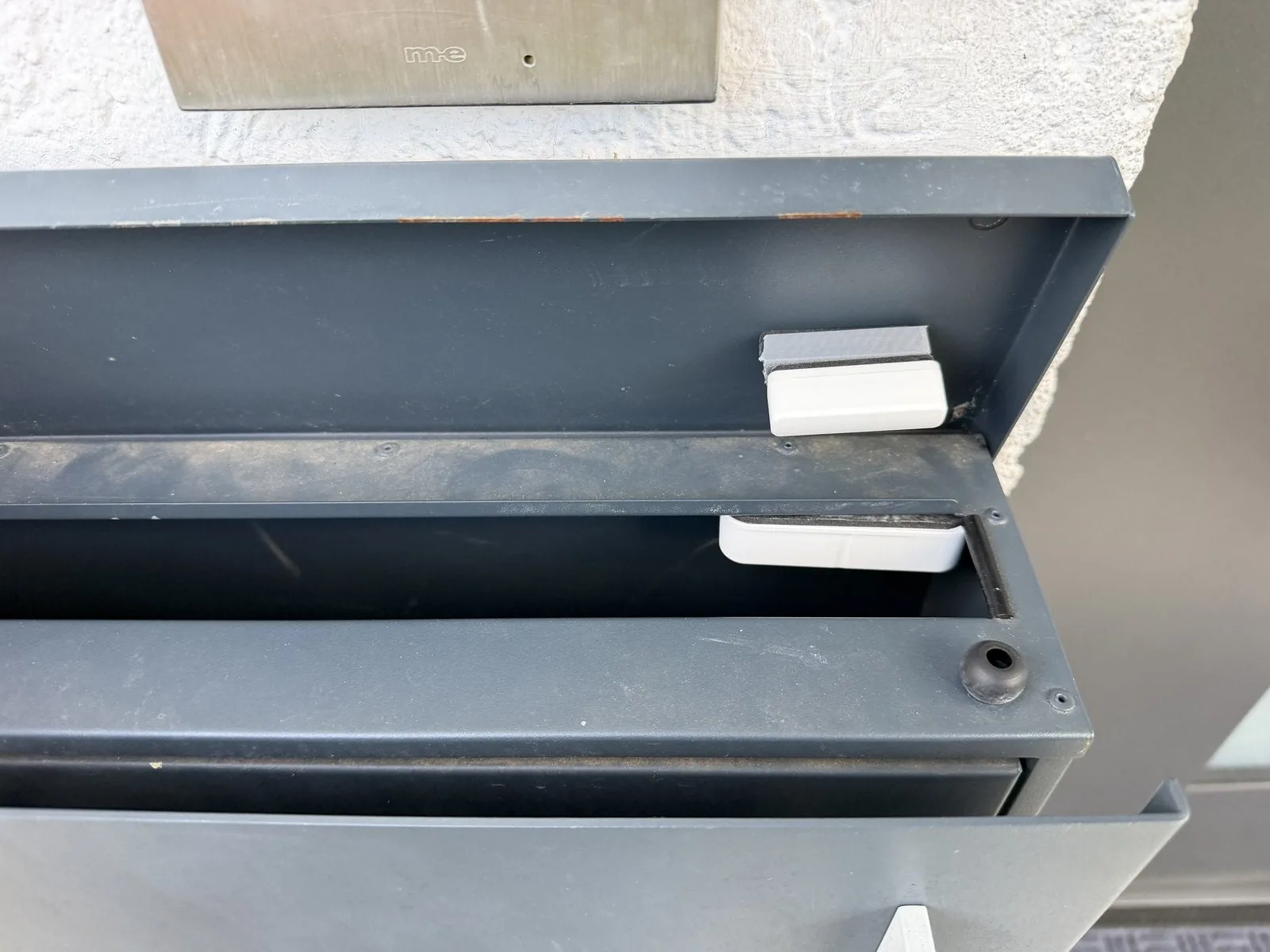 Sensor con su imán montados en el interior de la tapa del buzón, ambos sobre pequeños separadores