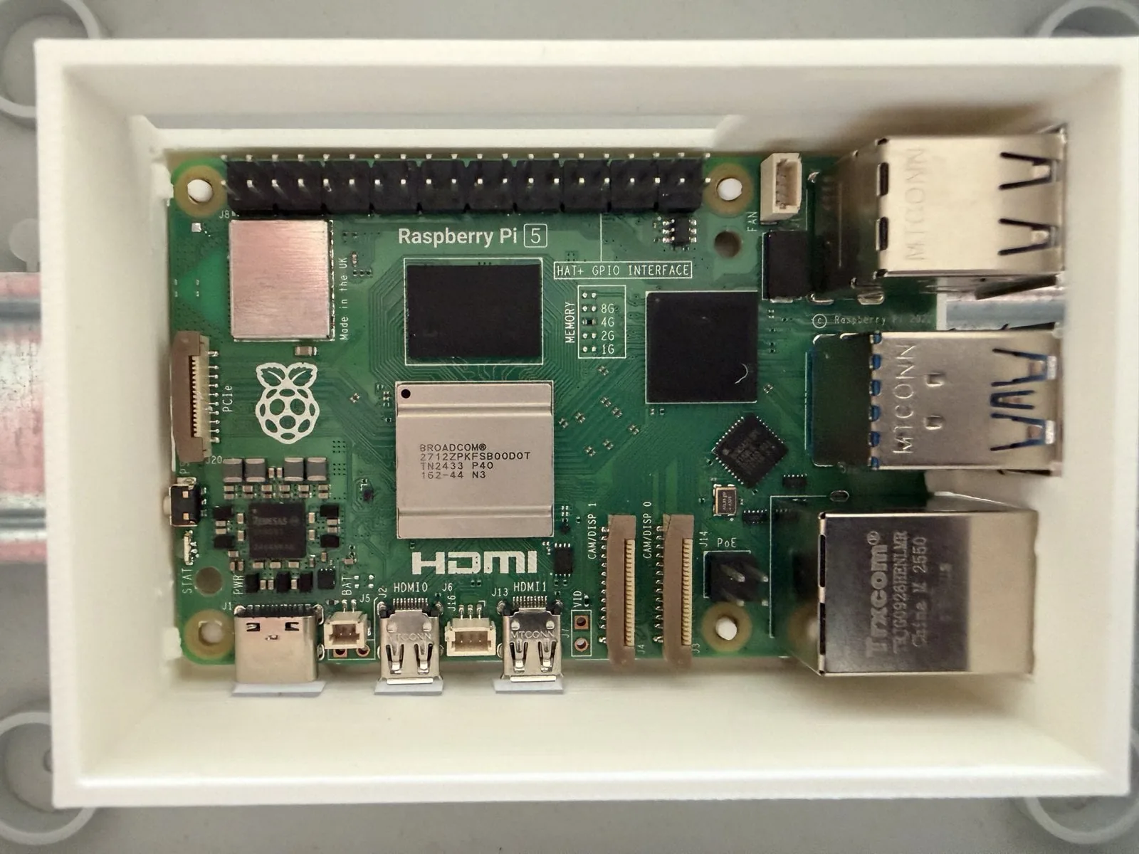 Raspberry Pi 5 ya montado en la bandeja sobre el riel, con todos los conectores calzados en sus ventanas