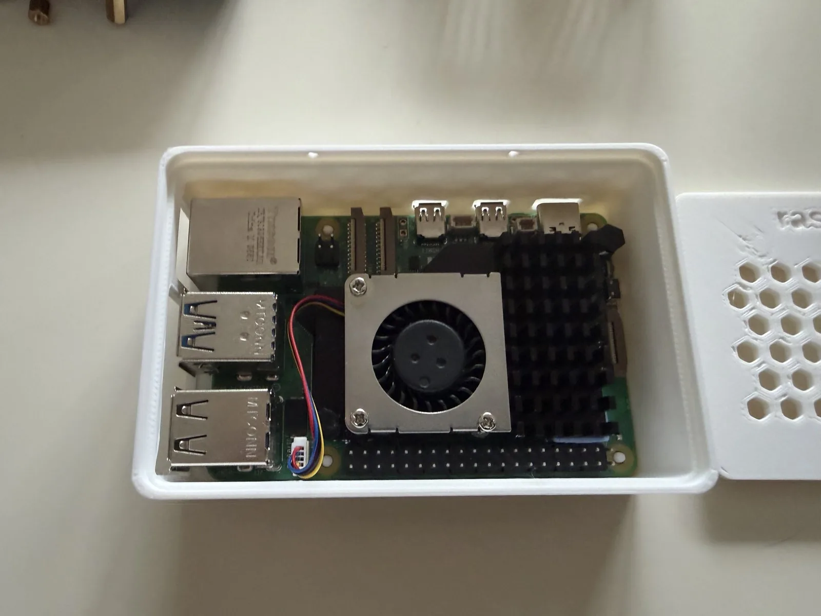 Raspberry Pi 5 con el Active Cooler oficial montado dentro de la carcasa impresa, con la tapa al lado