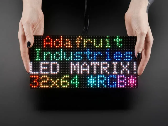Matriz LED RGB de 64x32 pixeles sostenida en las manos