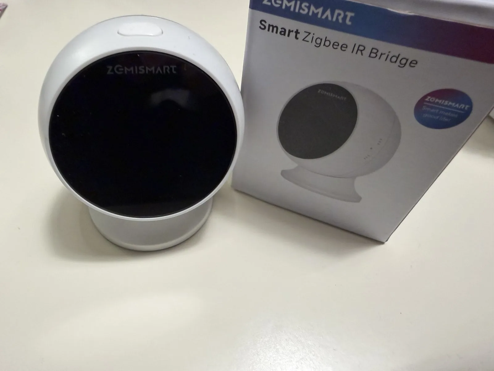 Blaster IR Zigbee junto a su caja sobre una mesa clara