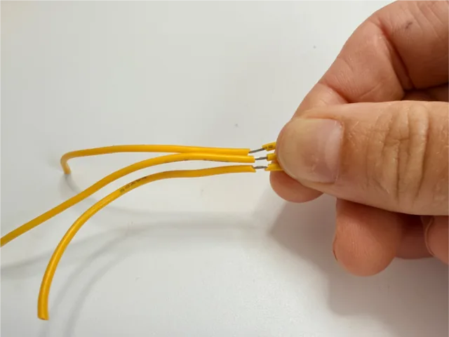 Extremos de una tira LED cortada, con los cables separados para soldar
