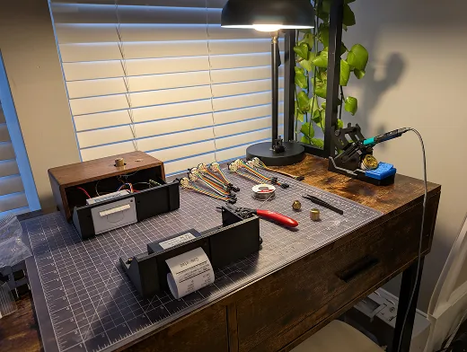 Banco de trabajo con la Raspberry Pi, la impresora termica, el chasis impreso en 3D y las piezas de la caja