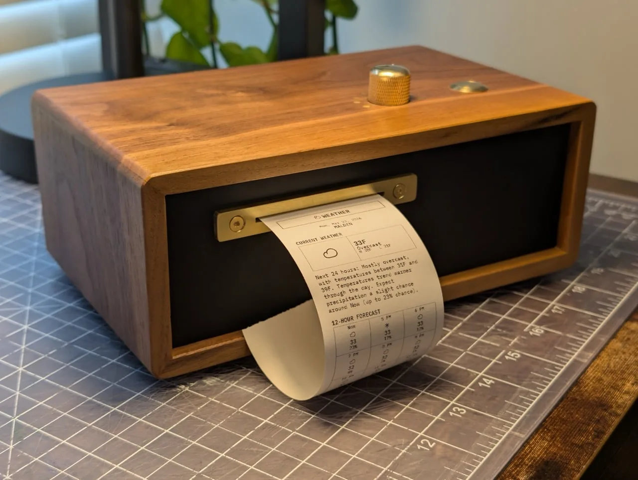 Paper Console de nogal y bronce imprimiendo un reporte del clima en papel termico