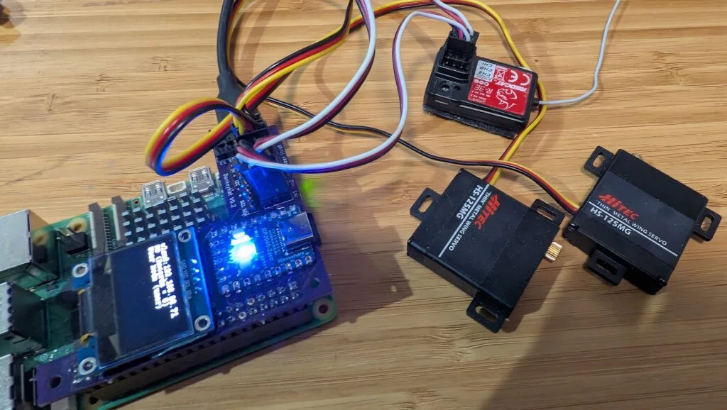 Raspberry Pi con el RC Hat montado, junto al receptor RC y dos servos Hitec listos para conectar