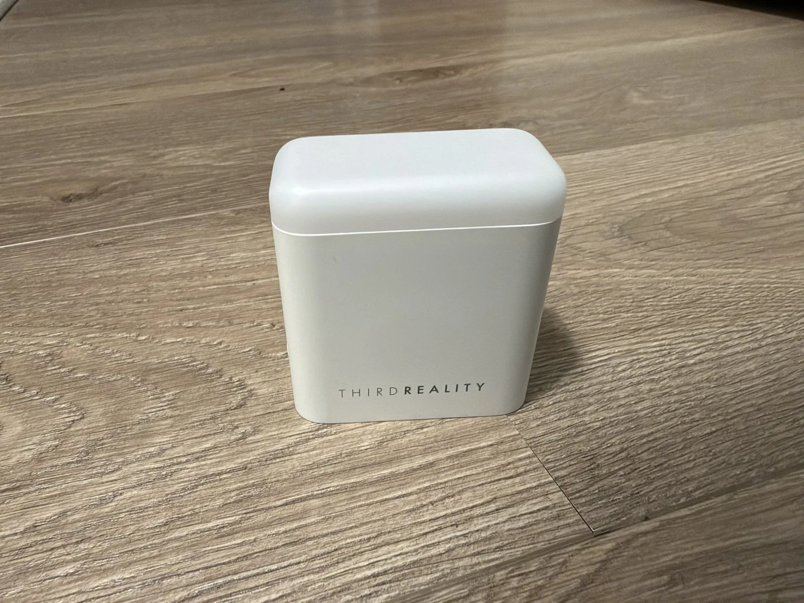 ThirdReality Smart Presence Sensor R3 visto de frente: carcasa blanca con tapa translúcida de la luz, sobre piso de madera