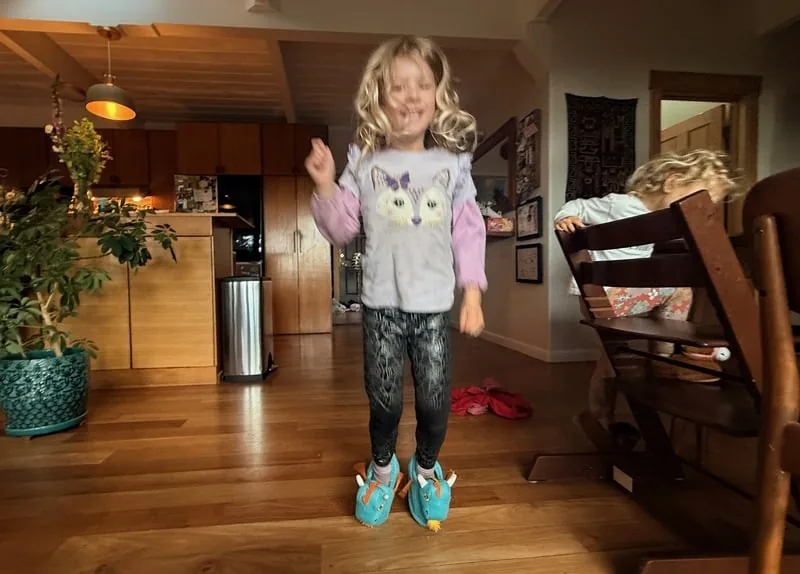 Niña saltando con las pantuflas de dragón puestas, mostrando la reacción a la pisada