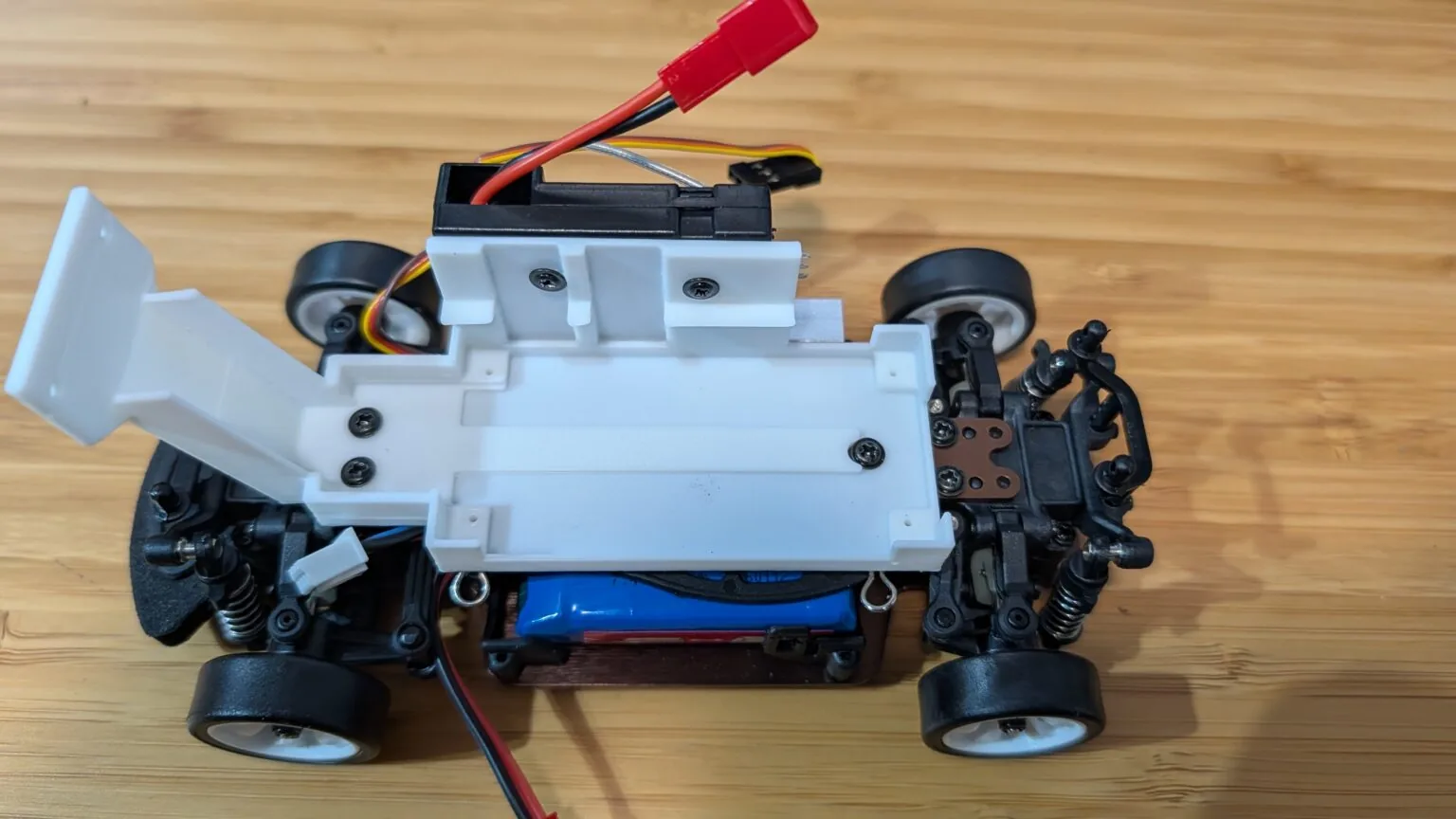 Soporte blanco impreso en 3D atornillado al chasis con el receptor RC reinstalado
