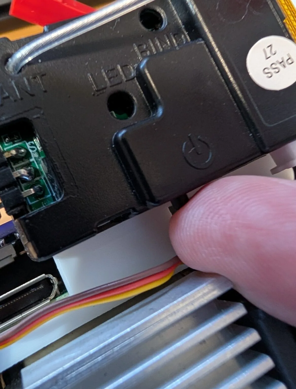 Dedo presionando el botón de encendido oculto en el receptor RC del auto