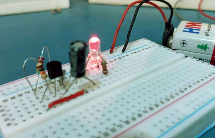 Prototipo del circuito armado en protoboard con el LED rojo encendido, los transistores BC547 y la pila de 9V