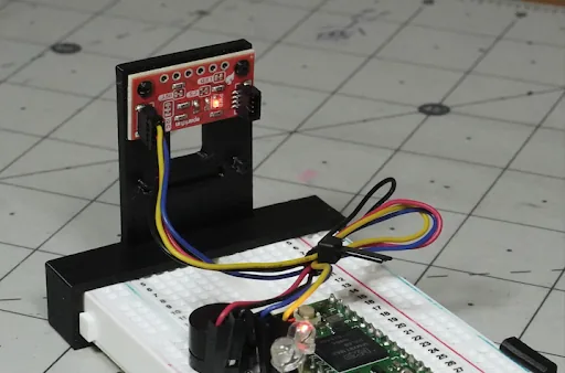 Versión mini del sensor montada en su soporte impreso, apuntando a través de la pieza
